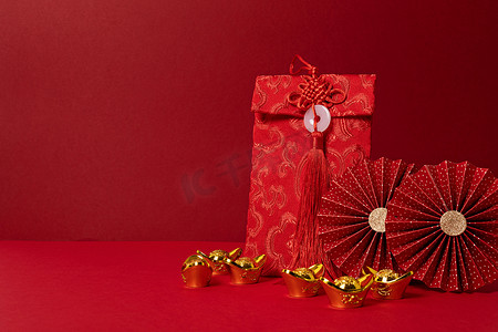 纸扇手绘摄影照片_中国新年装饰比红色背景。传统的农历新年红包，金锭，纸扇