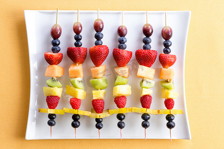 热带水果拼盘摄影照片_Healthy fresh shish kebab fruit treats