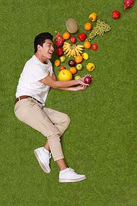 水果新鲜不新鲜摄影照片_青年男女拿着水果躺在草地上