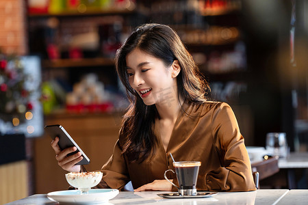 咖啡馆内边喝咖啡边使用手机的青年女人