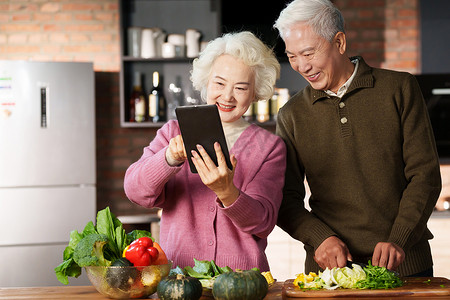 做饭的老年夫妇使用平板电脑