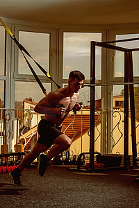 男子与裸躯干, 肌肉强健的胸部在健身房享受训练, trx。运动员, 运动员, 肌肉男子汉做锻炼与 trx 循环, 窗口在背景。体育和健身房概念.