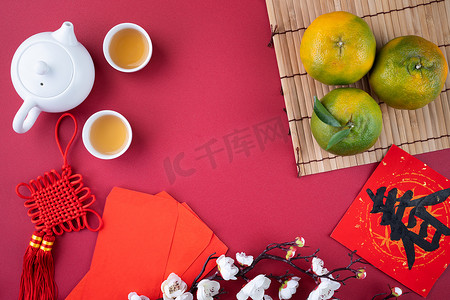 在中国农历新年水果的概念中，新鲜成熟的橘子和鲜叶放在红色桌子的背景上，中文意思是春天.