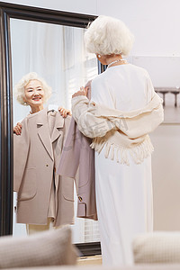 狭叶珍珠菜摄影照片_时尚的老年人拿着新衣照镜子