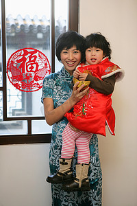 剪纸大鼓摄影照片_中国年轻妈妈抱着孩子