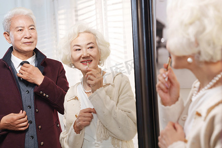 时尚的老年夫妇对着镜子穿衣打扮