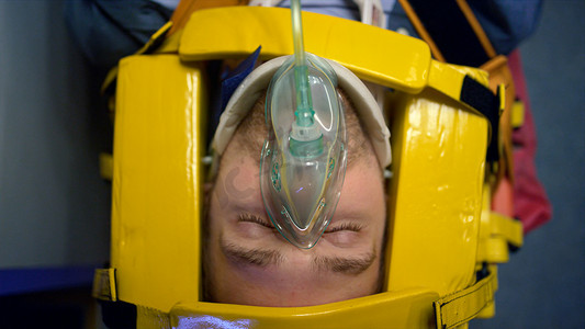 戴氧气面罩的男人躺在担架上.为人类提供急救的医护人员