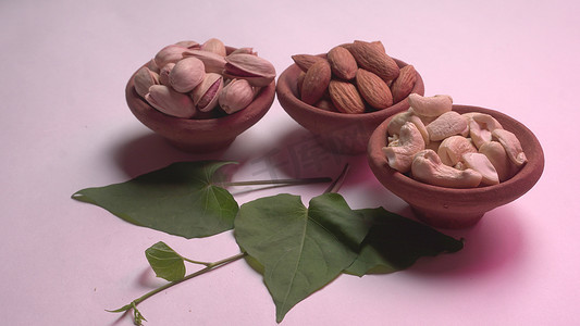 Assorted nuts with green leaves on studio background