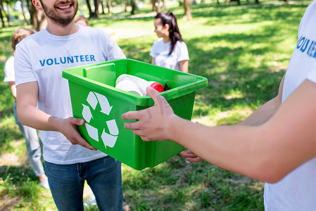 绿色回收箱中的男性青年志愿者裁剪视图