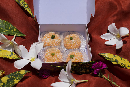 饰物摄影照片_橙色的khoprapak印度独特的融合糖果。从糖果店买的礼品盒里赠送.用开心果装饰的橙子形甜饰物，装饰着花朵节庆的样子