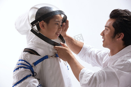 中国航天背景摄影照片_青年男人给小男孩穿宇航服