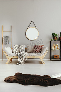 棕色愤怒地毯在时尚的 ethno 客厅的白色地板与斯堪的纳维亚沙发枕头和毯子, 真正的照片与复制空间在空米色墙