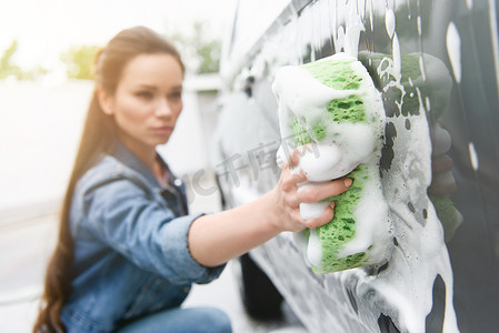 有吸引力的妇女清洁车在洗车用抹布和泡沫