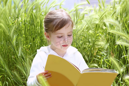 读本书摄影照片_阅读本书绿色尖峰花园小金发女孩
