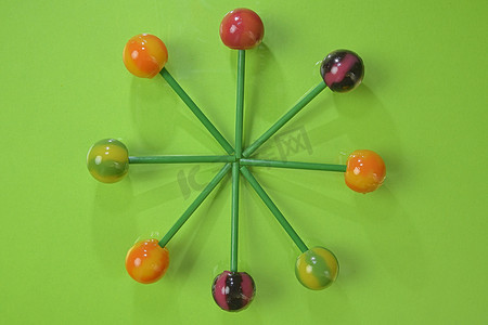 pop标价签摄影照片_Tasty lollipops on green pastel color background. Set of realistic colorful lollipops on green plastic sticks. Summer and pop art concept. Top view. Real reflection
