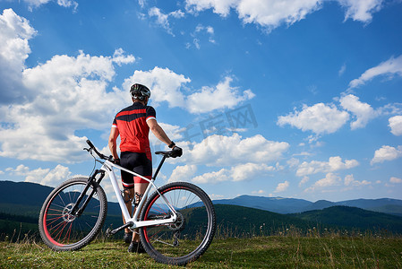  年轻的体育旅游车手在职业运动服开始骑自行车在遥远的山, 活跃生活方式和极限体育概念 