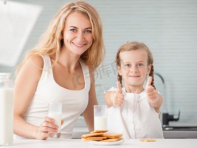 孩子和母亲摄影照片_孩子和母亲喝牛奶。幸福的家庭，在家里吃