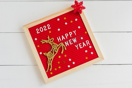 新的一年2022 。白色背景上有金鹿和红色片断的字母板。平躺在床上