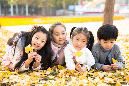 落叶草地摄影照片_可爱的男孩女孩在户外玩耍