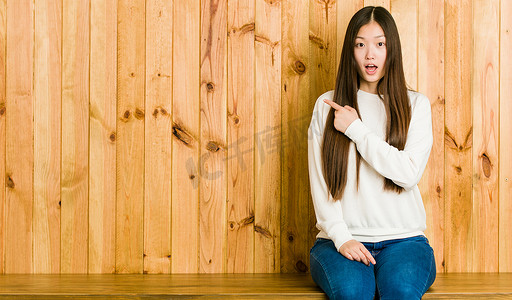 年轻的中国女人坐在一个指向侧边的木制地方