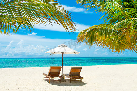 美丽的海滨沙滩日光浴浴床与撑着雨伞，印度洋马尔代夫岛