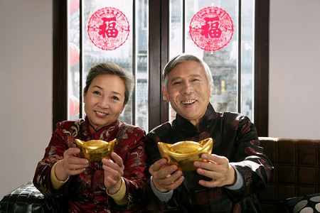 中国老年夫妇手捧元宝拜年