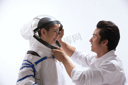 光荣的摄影照片_青年男人给小男孩穿宇航服