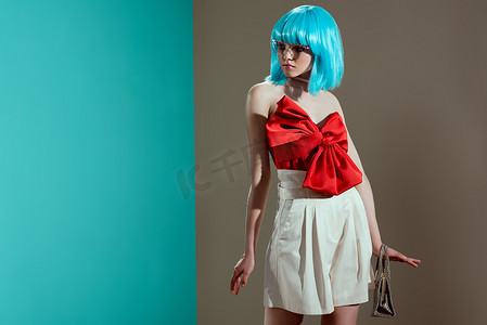 漂亮弓摄影照片_漂亮的年轻女性模特在蓝色假发和红弓看着远离工作室
