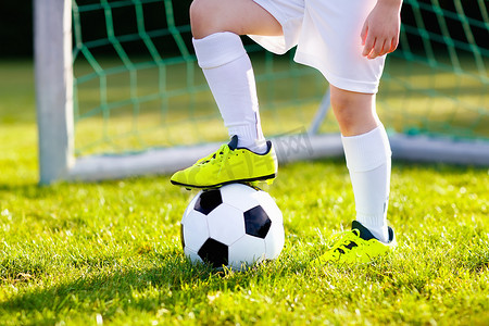 孩子们在户外运动场踢足球。孩子们在足球比赛中进了一球.小男孩在踢球。穿着队服和紧身衣跑步的孩子。学校足球俱乐部。对年轻运动员的体育培训.