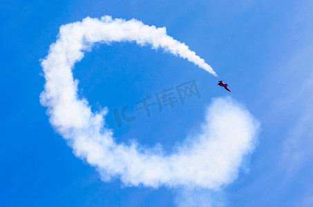 红色烟雾摄影照片_红色的打击战斗机，有白色圆圈烟雾背后在蓝蓝的天空