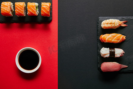 平躺与酱油在碗里, 寿司套上黑色石板板上的红色和黑色背景