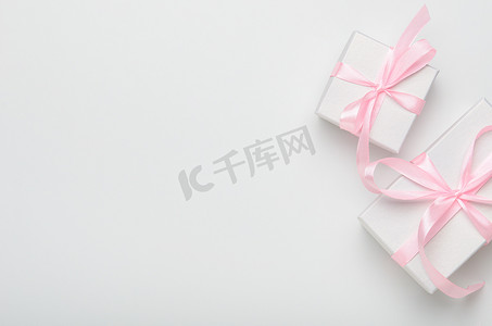 白色背景上有粉色带子的礼品盒。概念节日礼物，恭喜你。顶视图、复制空间、平面布局.
