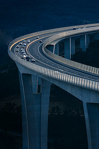 全球运输和物流连接。现代和未来派高速公路上的繁忙交通。高弯桥，落日下的工程杰作.