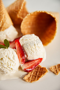 华夫饼圆锥和美味的融化冰淇淋与草莓在灰色的特写视图