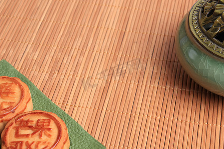 月饼上摄影照片_中国月饼和香炉在竹子背景上.亚洲传统的中秋节。象形文字的翻译：芒果、石榴和荷花.