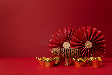 中国新年装饰比红色背景。传统的农历新年金锭，纸扇，老虎。复制空间