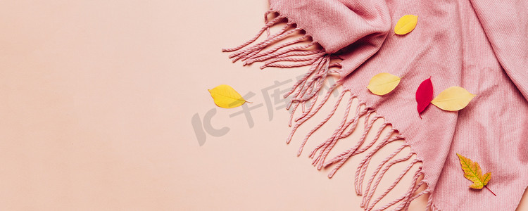 粉红舒适的围巾，上面有流苏和散落的叶子