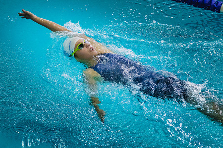 young beautiful girl athlete swims backstroke