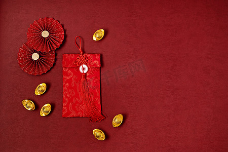 中国新年装饰比红色背景。传统意义上的农历新年红包，纸扇，金锭与文字意味着好运，繁荣，财富。平躺在地上，俯瞰四周