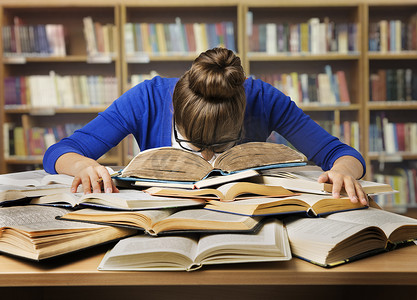 学生在学习上的书，睡觉累女孩读图书馆的书