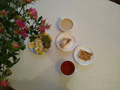 roses摄影照片_Breakfast for two with tea and cakes with roses in a vase