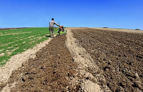 农民加工着一个春天的田野的路障. 
