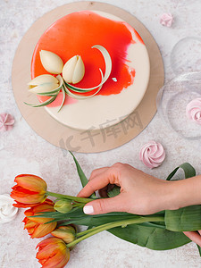 女性手捧红色郁金香, 白色和红色装饰蛋糕, 蛋白甜饼和丝带的食物构成