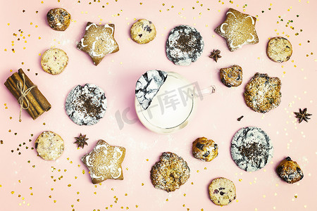 冬季假日食品组合与不同类型的传统自制圣诞饼干与一杯牛奶粉红背景。手工制作的新年甜糕点。圣诞烘焙。平躺在床上