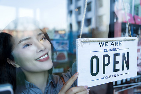 咖啡店标志摄影照片_咖啡店的女服务员挂营业标志