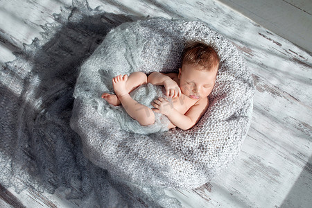 襁褓摄影照片_熟睡的婴儿男孩襁褓在巢里