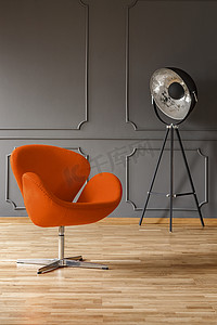 相片夹相片摄影照片_真实相片橙色扶手椅和大金属演播室灯站立在黑暗的客厅内部与木地板和塑造在墙壁上