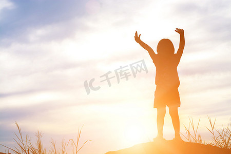 小女孩伸出手来显示在日落时的喜悦和幸福 .