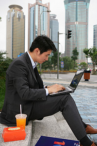 上海浦东写字楼旁一位男商务人士使用笔记本电脑时吃洋快餐