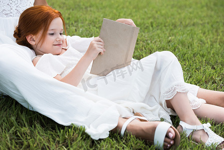 母亲读本书在公园里的女孩
